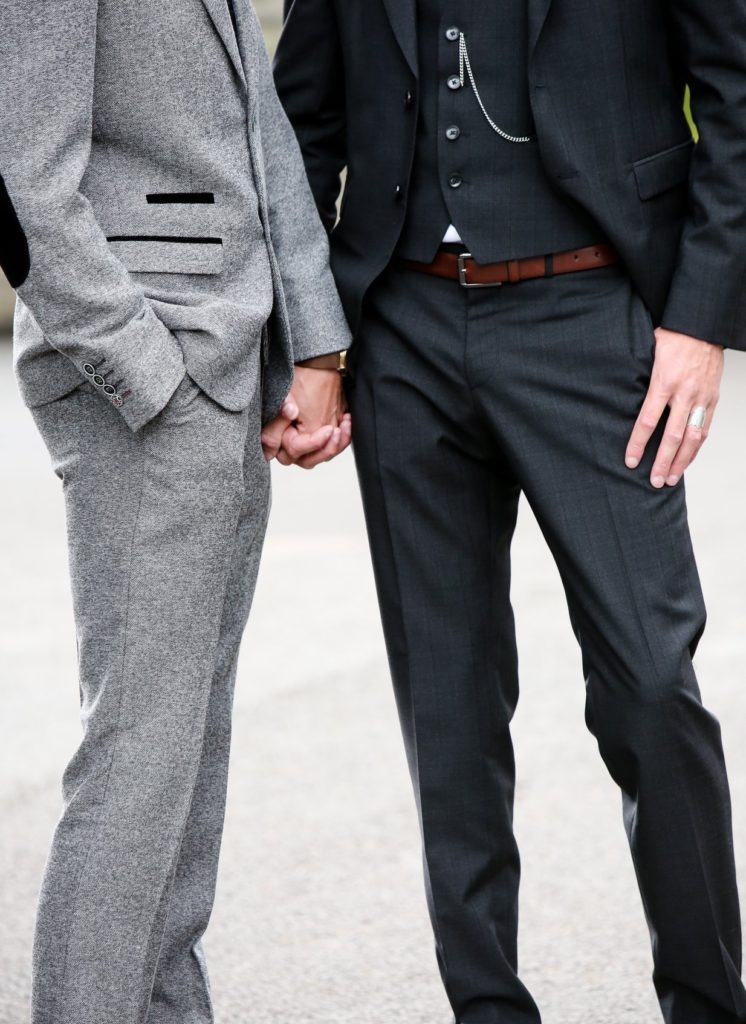 close up of gay couple with linked hands at their wedding
