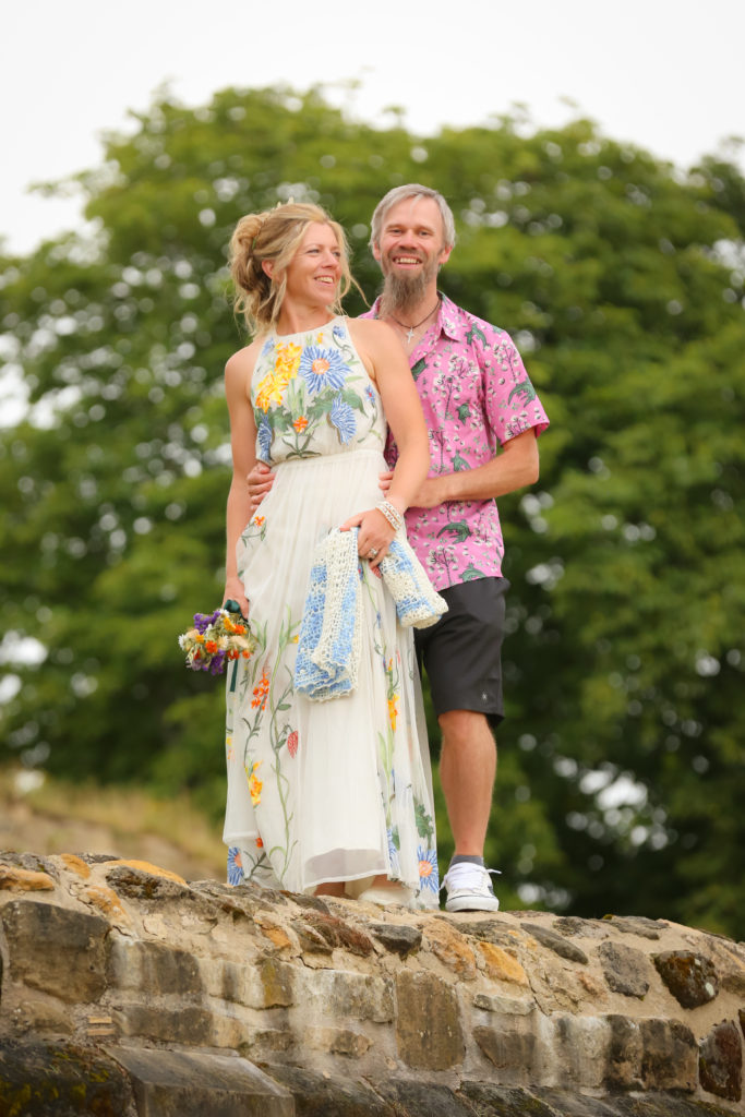 alternative bride and groom colourful on wall infront of trees