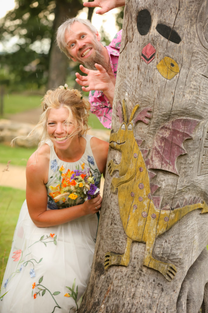 playful bridge and groom shot behind a totem pole