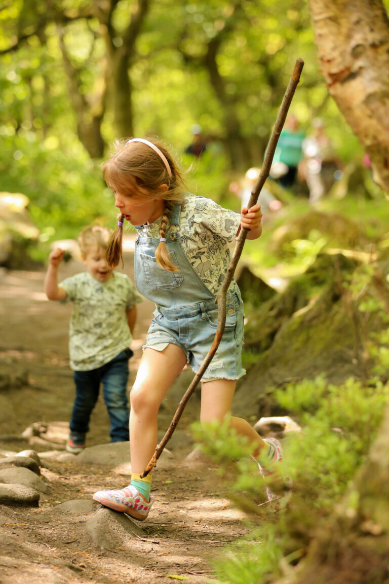 girl exploring woods with stick during photo shoots