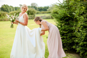 bridesmaid sorting out brides wedding dress