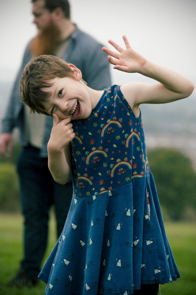 young lad in dress waving to camera