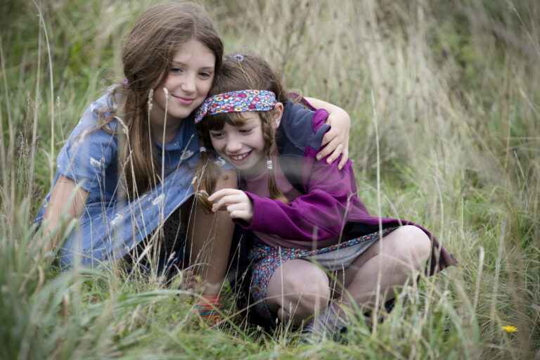 sisters on family shoot hugging in grass