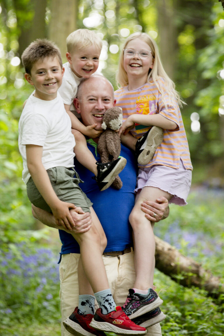 Father lifting smiling children during natural family photo session