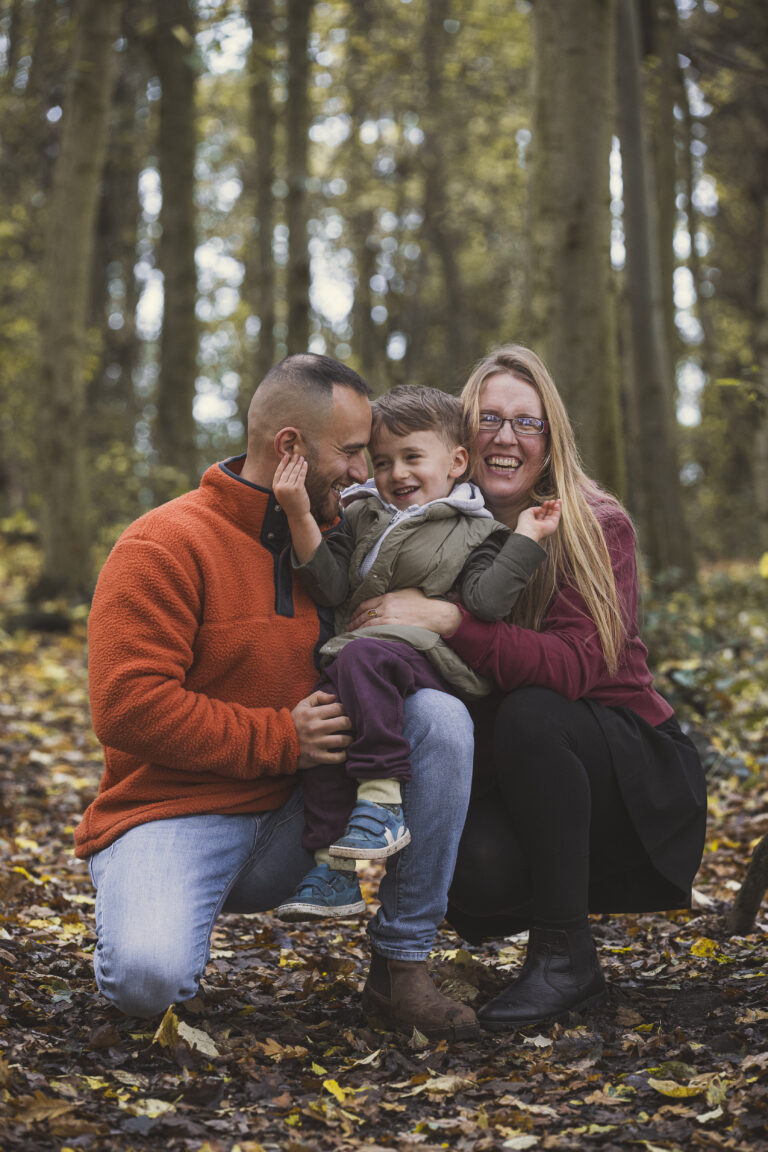 mum dad and son hugging in natural woodland family photo shoot