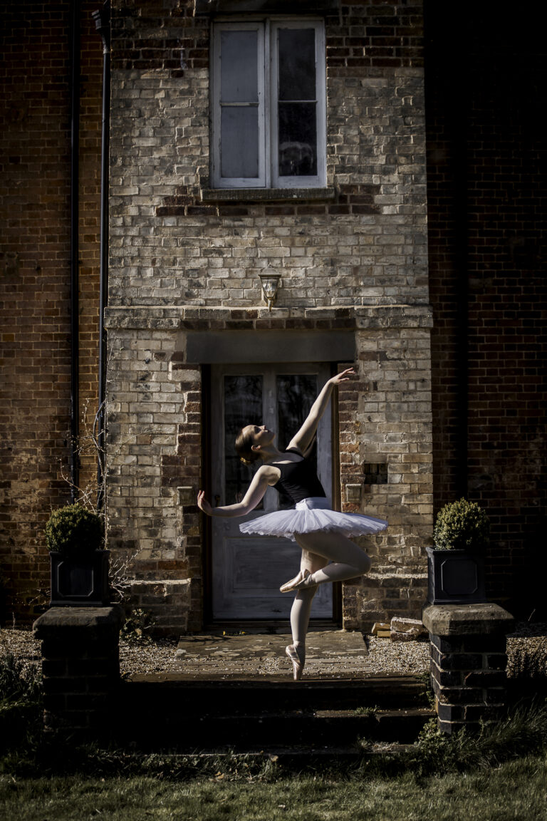 Ballet dance, in pose with arm outstretched in point shoes with a cup of tea and @agentlemensresidence in background