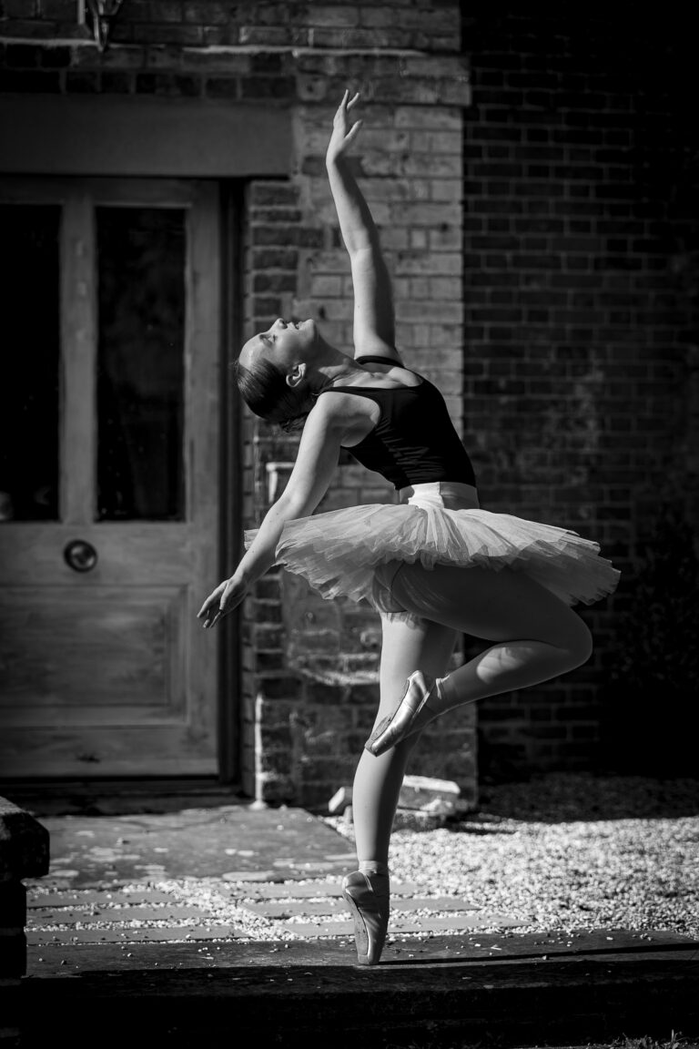 Ballet dance, in pose with arm outstretched in point shoes with @agentlemensresidence in background