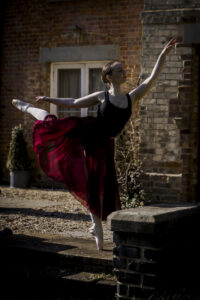 Ballet dancer, in pose with arm outstretched in point shoes @agentlemensresidence in background