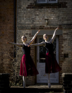 2 ballet dancers, in pose with arms outstretched in point shoes @agentlemensresidence in background
