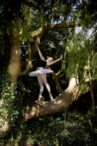 @agentlemansresidence house in the background. Ballet dancer in pose on tree branch.