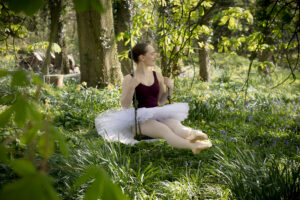 Ballet dancer in dappled sunlight on a swing.