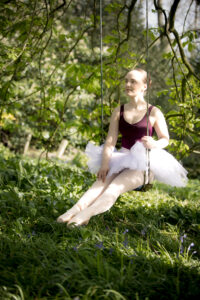 Ballet dancer in dappled sunlight on a swing.