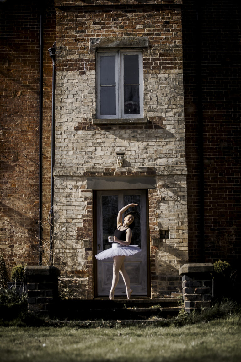 Ballet dance, in pose with arm outstretched in point shoes with a cup of tea and @agentlemensresidence in background