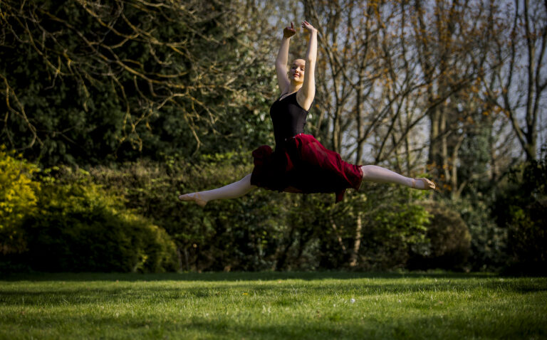 Ballet dancer in splits pose, in garden. sunlight.