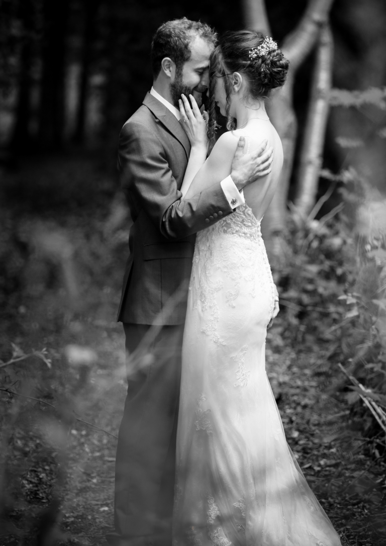 Black and white photo of a bride and groom forehead to forehead in woodland, by Nottingham wedding photographer Ali J